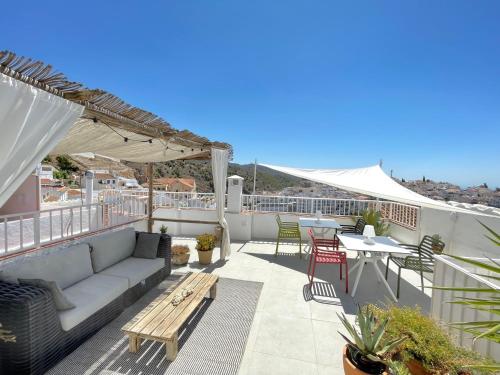 um pátio com um sofá e mesas no telhado em Los Nidos Apartments, Frigiliana em Frigiliana
