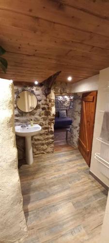 une salle de bain avec un lavabo et un mur en pierre dans l'établissement Les Gîtes du Couvent, à Nozières