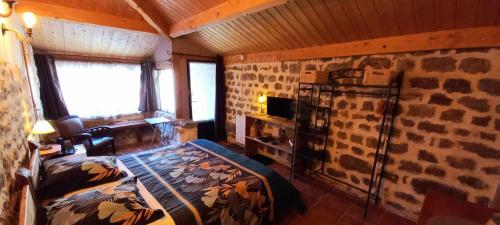 une chambre avec un lit et un mur en pierre dans l'établissement Les Gîtes du Couvent, à Nozières