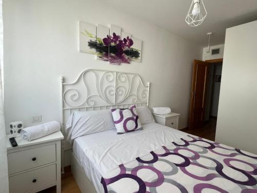 - une chambre dotée d'un lit blanc avec un couvre-lit violet et blanc dans l'établissement El Llano 2 ideal para descansar, à Puebla de Alfindén