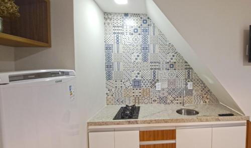 a kitchen with a sink and a mosaic wall at Flat da Eliete e Admilson 2 in Porto Seguro