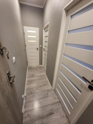 ein Flur mit einer weißen Tür und einem Holzboden in der Unterkunft KOŁOBRZEG Jana Pawła 19 mieszkanie 2 pokojowe in Kołobrzeg