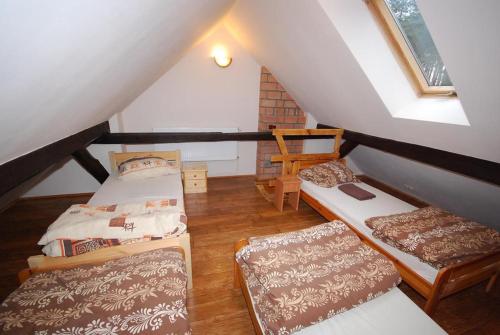 a attic room with three beds and a chair at Noclegi Dorotowo in Dorotowo