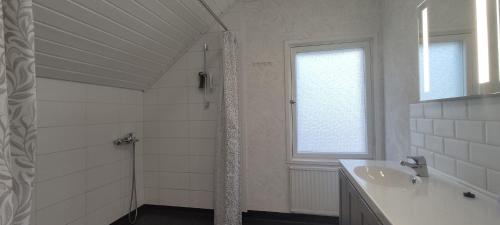 baño blanco con ducha y lavamanos en Kortteer vihreä huone en Rauma