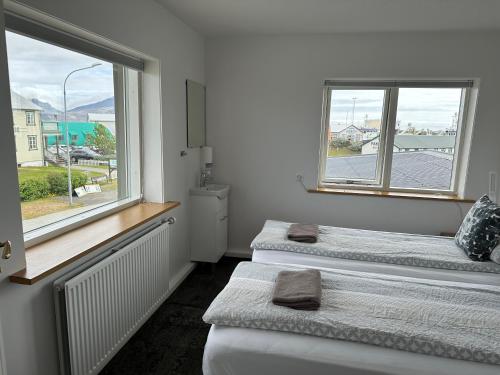 two beds in a room with two windows at Guesthouse Dyngja in Höfn