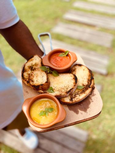 a person holding a plate of food with tomatoes and bread at Dolphin Hotel in Fernando de Noronha