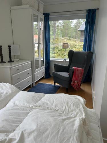 a bedroom with a bed and a chair and a window at Joängets Fjällgård 18a in Sälen