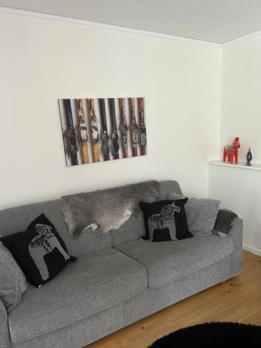 a gray couch in a living room with baseball bats on the wall at Joängets Fjällgård 18a in Sälen