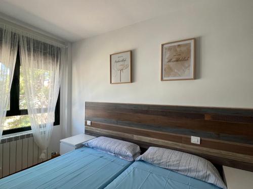 a bedroom with a bed with a wooden headboard and a window at NUEVO LLANO JOB&FAMILY in Puebla de Alfindén