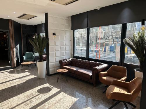 a living room with a leather couch and two chairs at Hotel EUROPACITY in Brussels