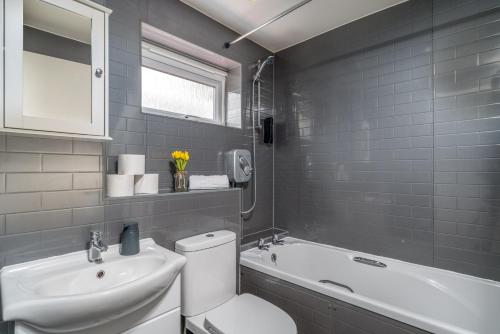La salle de bains est pourvue de toilettes, d'un lavabo et d'une baignoire. dans l'établissement Crawley Atkinson Pet Friendly 1-Bedroom Apartment, à Three Bridges