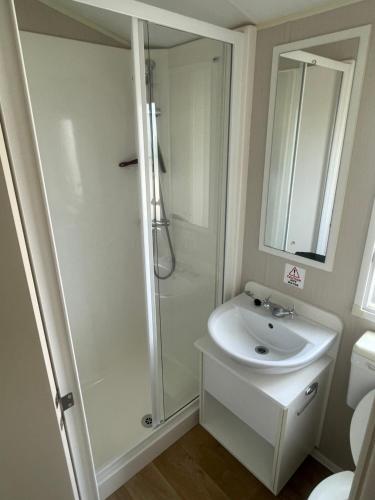 baño blanco con ducha y lavamanos en The Sunnyside Retreat en Whitstable