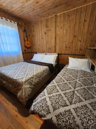 two beds in a room with wooden walls at Colina Branca in Rio Rufino