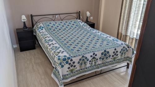 a bed with a blue and white blanket on it at Beachfront Apartment in Nea Moudania