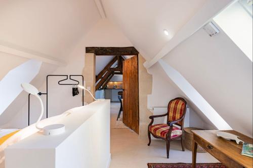 Pokój na poddaszu ze schodami i krzesłem w obiekcie Bagatelle avec Jardin et Piscine Chauffée w mieście Biéville-en-Auge