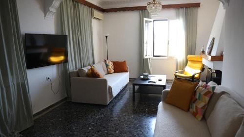 a living room with a couch and a tv at Demie and George Ηouse in Loutraki
