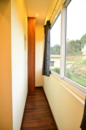 a hallway with a window and a wooden floor at Lasinara inn in Yercaud