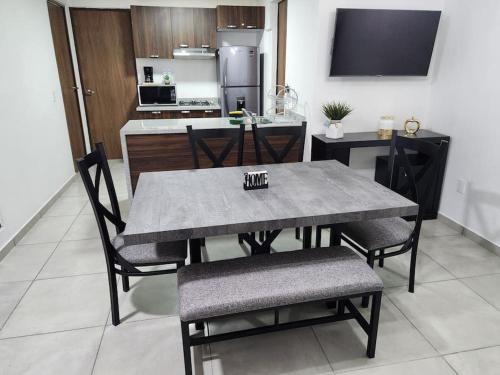 a dining room table and chairs with a kitchen in the background at Amplio departamento con alberca in Guadalajara