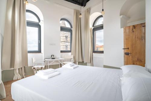a white bedroom with a large white bed and windows at Torre Subrosa, vasca in camera cromoterapia in Viterbo
