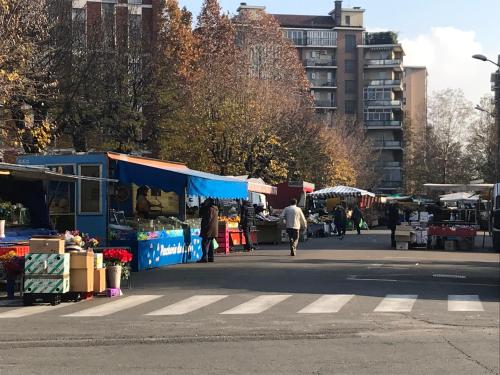 an open air market with people walking on a street at Albergo Guido Reni in Turin