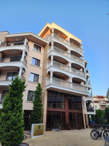 a tall apartment building with a tree in front of it at VALENCIA GARDENS STUDIO LUX 4 per. in Nesebar