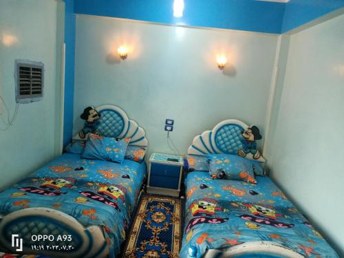 two beds in a bedroom with blue walls at sun Ahmed hotel in ‘Ezbet Abu Ḥabashi