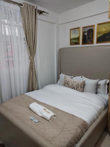 ein Bett mit zwei Handtüchern und einem Fenster in der Unterkunft Zoe Homes Oak Villa Apartment 1 and 2 Bedroom 201 in Kericho
