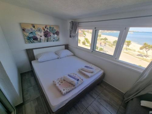 a small bedroom with a bed with a view of the beach at Apartments Kovač in Vir