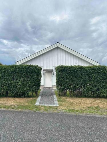 a white barn with a white door and some bushes at Studiolägenhet i Höga Kusten in Ullanger
