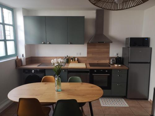 cocina con mesa de madera con sillas y nevera en Appartement central maison Marceau, en Rivesaltes