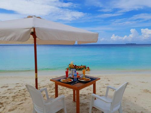 un tavolo e sedie in spiaggia con ombrellone di Nemo Inn a Omadhoo