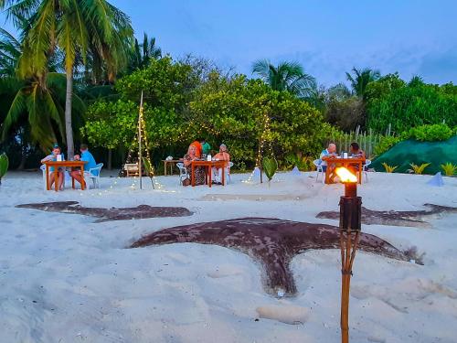 a starfish on the beach with people sitting at tables at Nemo Inn in Omadhoo