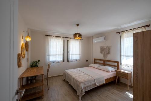 a bedroom with a bed and a table and windows at Stone House Datça Blok-A in Datca