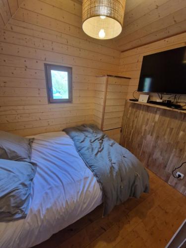 a bedroom with a bed and a flat screen tv at Chalet du bonheur de campagne 