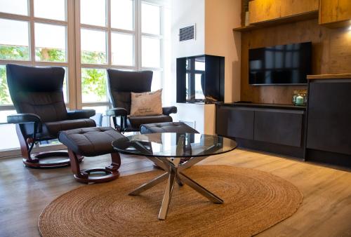 a living room with a glass coffee table and chairs at Ferienwohnung "Landhaus Buchenallee" in Bad Bentheim