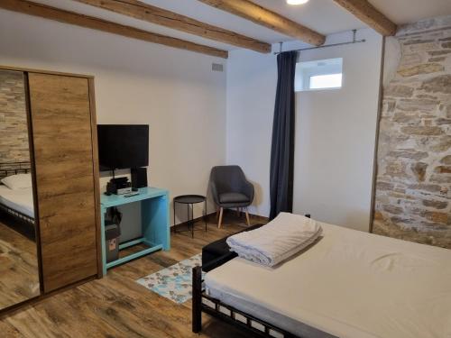 1 dormitorio con 1 cama, TV y silla en Villa Carmen, en Pula
