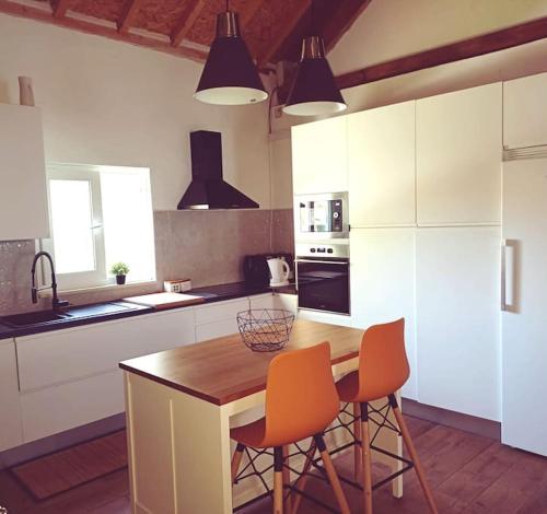 a kitchen with a wooden table and two orange chairs at Casa da Ribeira in Alcanede