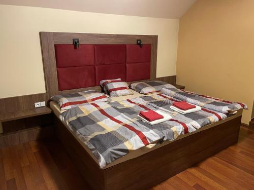 a bed with a red headboard and pillows on it at RRR Apartmány 3 in Bojnice