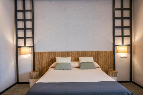 a bedroom with a large white bed with two pillows at Hotel El Coto De Quevedo in Torre de Juan Abad