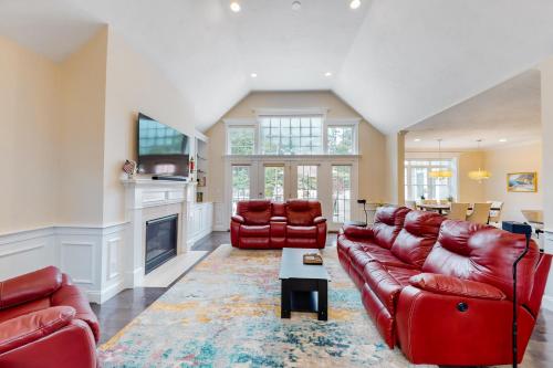 a living room with red leather furniture and a fireplace at Cape Castle in Mashpee