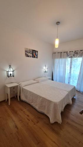 a white bedroom with a large bed and two windows at Las Runas in Sobrepiedra