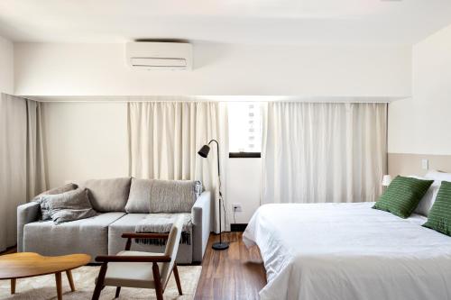 a white bedroom with a bed and a couch at Tabas - Melia Confort in São Paulo