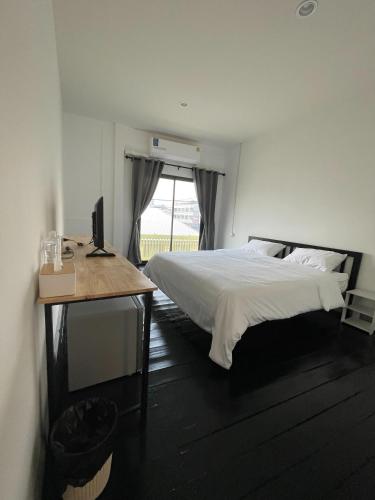 a bedroom with a bed and a desk and a window at GO INN HuaHin โกอินน์ หัวหิน in Hua Hin
