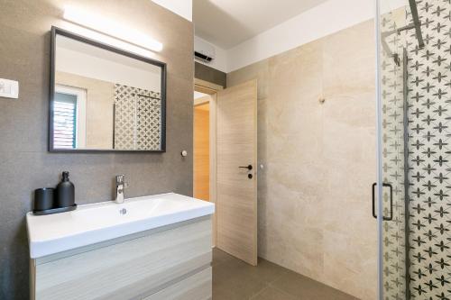 une salle de bain avec un lavabo blanc et une douche dans l'établissement Apartment near the beach- Zen 2, à Brna