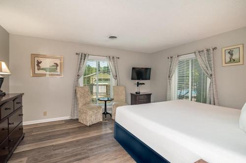 ein Schlafzimmer mit einem Bett und einem Stuhl und einem Fernseher in der Unterkunft Litchfield Country Club Cottage 4BR 4BA Retreat in Pawleys Island