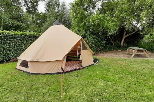 ein Zelt auf einem Feld mit einem Picknicktisch in der Unterkunft Sfeervolle Tipi tent dicht bij de kust. in Schagerbrug