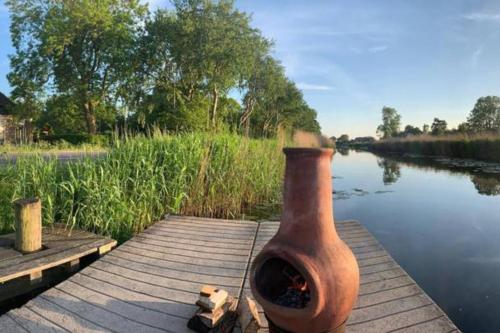 a pot sitting on a dock next to a river at Sfeervolle Tipi tent dicht bij de kust. in Schagerbrug
