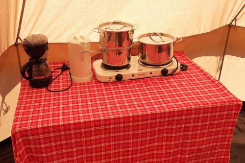 einem Tisch mit zwei Trommeln auf einem roten karierten Tischtuch in der Unterkunft Sfeervolle Tipi tent dicht bij de kust. in Schagerbrug