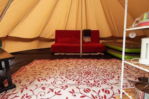 eine rote Couch in einem Zelt in der Unterkunft Sfeervolle Tipi tent dicht bij de kust. in Schagerbrug