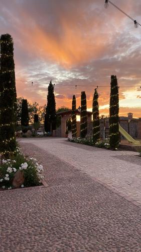 eine Backsteinstraße mit Bäumen und einem Sonnenuntergang im Hintergrund in der Unterkunft Hotel El Coto De Quevedo in Torre de Juan Abad